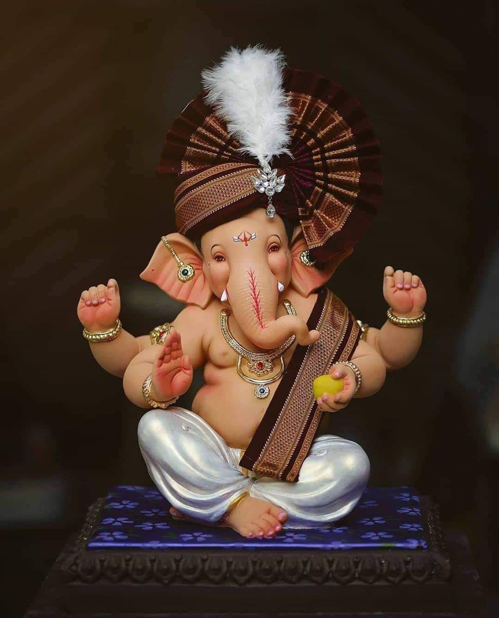 Statue eines kleinen elefanten mit einer feder auf dem kopf (ganesha, ganpati bappa, gott)