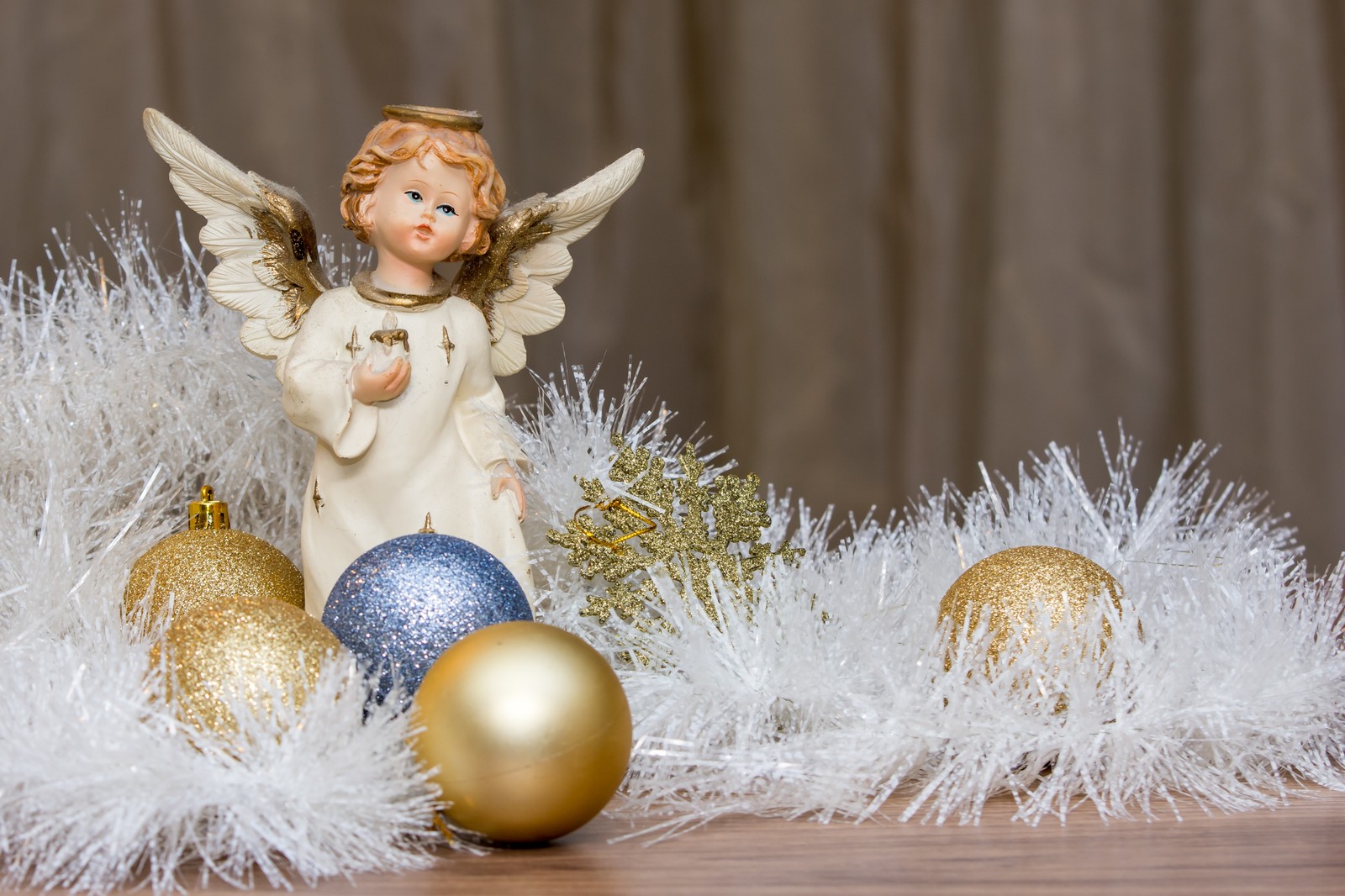 Uma pequena figura de anjo com um halo dourado e uma bola de natal azul e branca (anjo, angeli, angelo, anjos, pássaro)