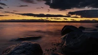 Atardecer sereno sobre aguas costeras con nubes dramáticas