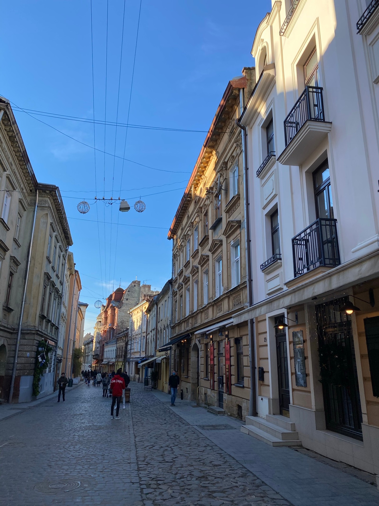 Une rue arabe avec des gens marchant dessus et un tram au loin (route, fenêtre, ville, quartier, infrastructure)