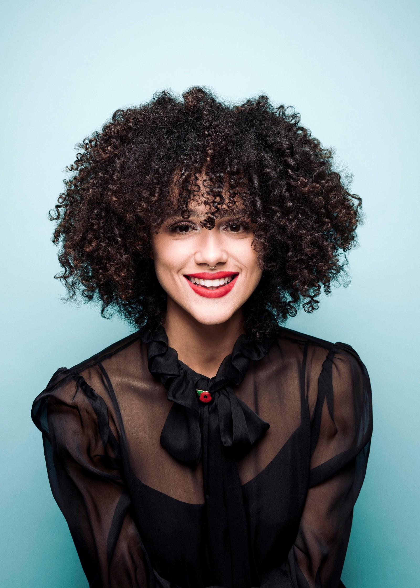 Femme artistique avec des cheveux bouclés et un haut noir souriant (nathalie emmanuel, belle actrice, actrice britannique, portrait, 5k)