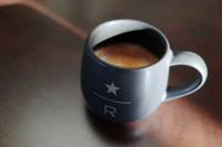 Elegant black coffee mug on a wooden table, showcasing a rich brew.