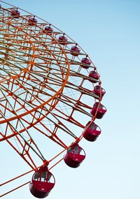 Rueda de la fortuna colorida contra un cielo despejado, simbolizando recreación y viajes en un parque de atracciones.