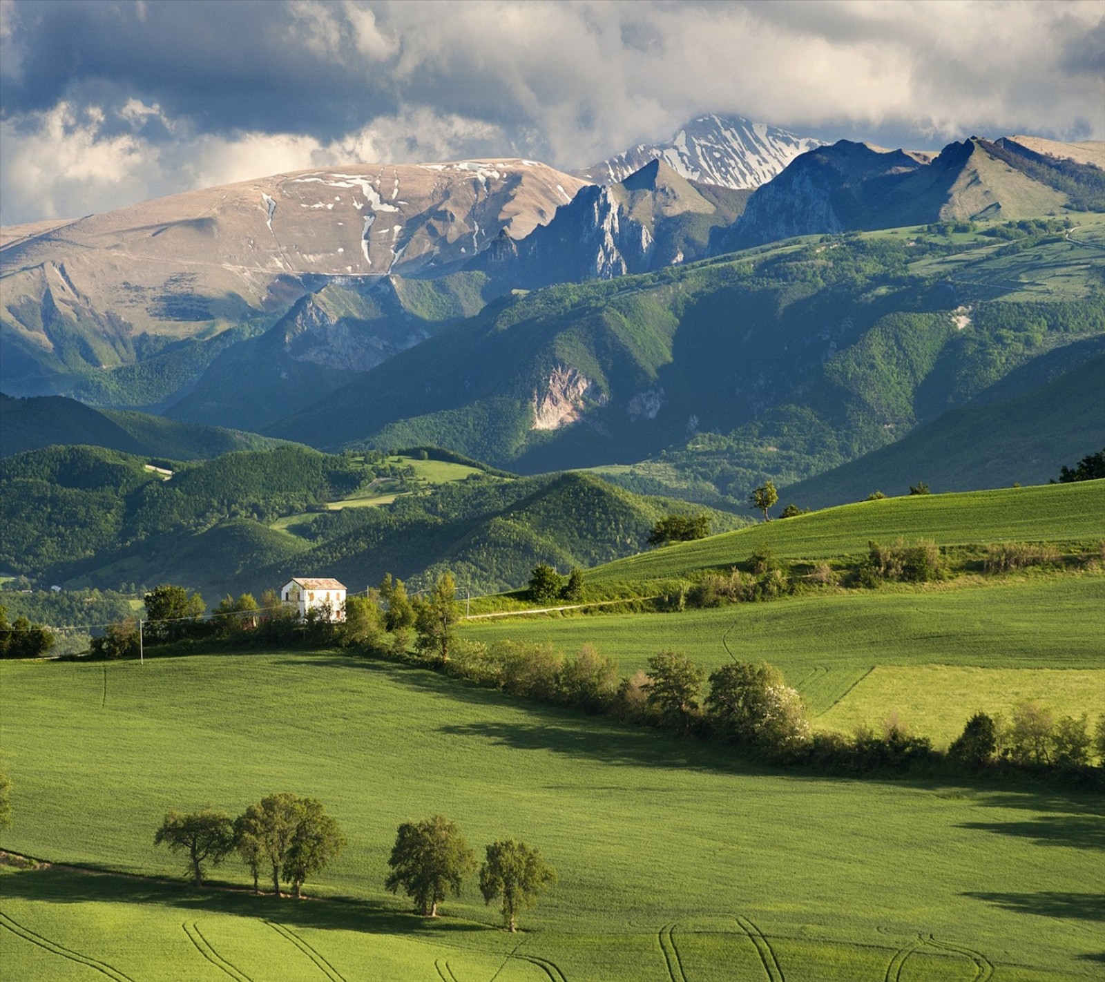 Montanhas e uma casa em um campo verde com algumas árvores (montanha, vista bonita)