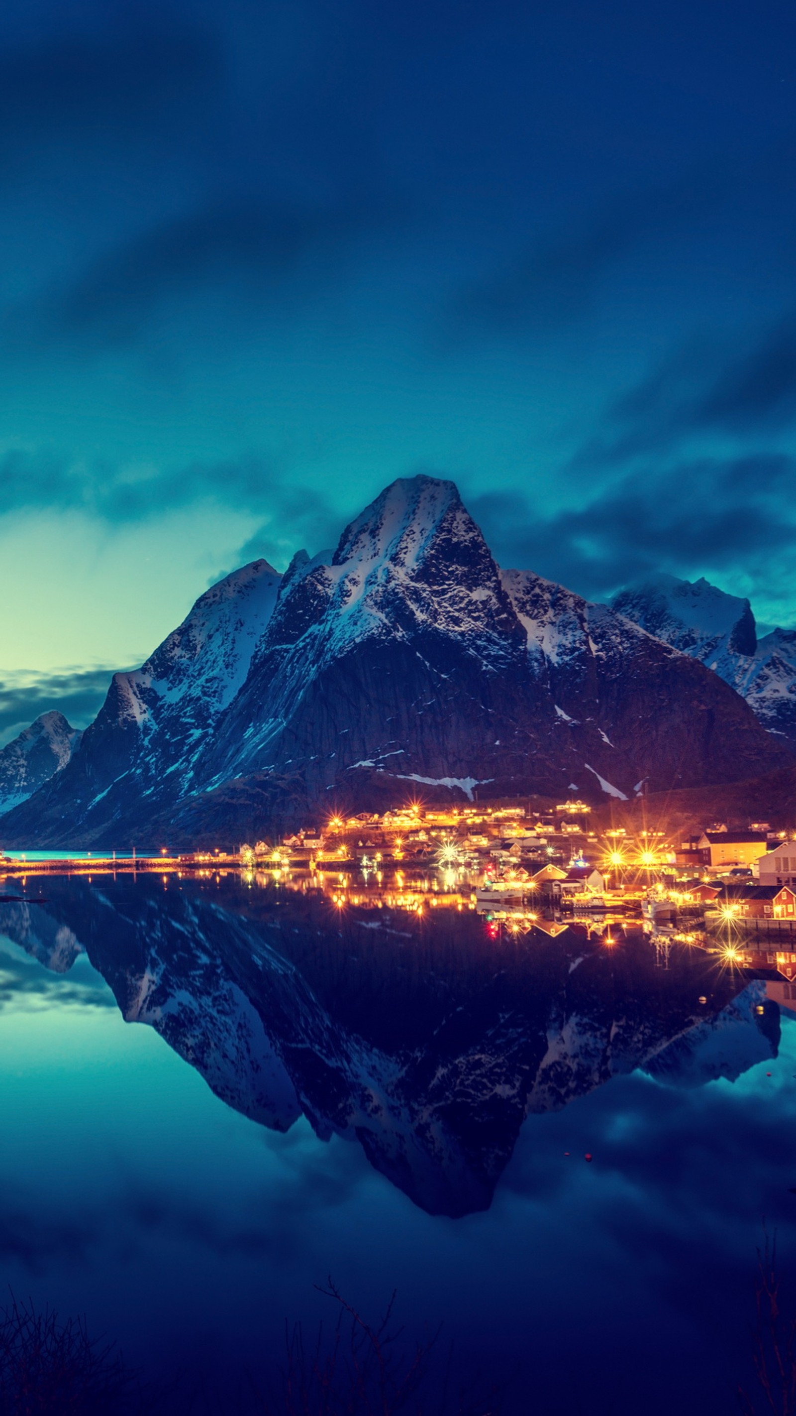 Montanhas refletidas em um lago à noite com uma cidade iluminada (montanha, noite, água)