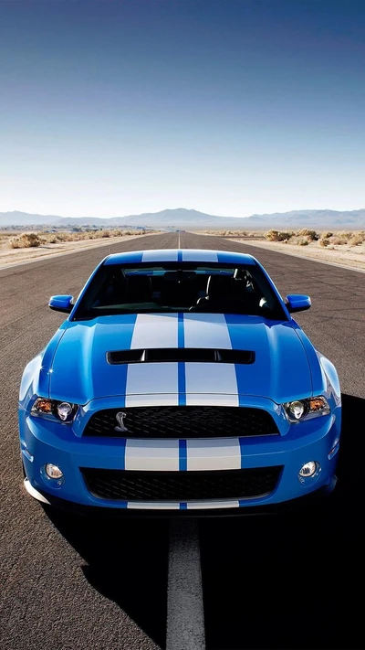 Ford Mustang Shelby GT500 2017 en azul llamativo con rayas blancas en una carretera desértica.