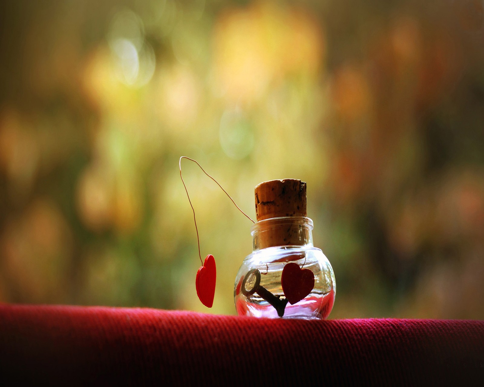 Une petite bouteille en verre avec un objet rouge à l'intérieur (aveugle, amour)