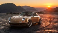 Classic Porsche 911 Targa at sunset with mountainous backdrop.