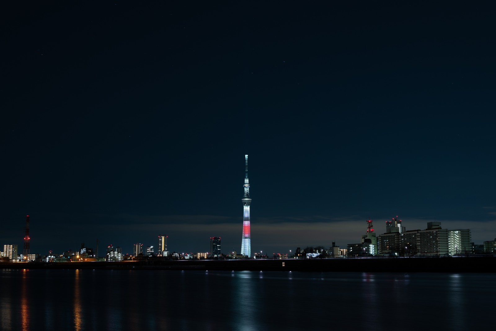 Vista atmosférica del horizonte de la ciudad de noche con una torre roja y blanca. (noche, tokio, tokyo, panorama, hito)