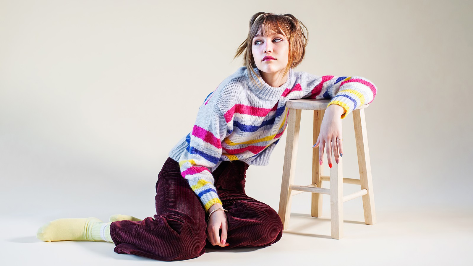 Une femme arabe assise sur un tabouret avec un pull coloré (grace vanderwaal, chanteur, célébrité, célébrités, femmes)