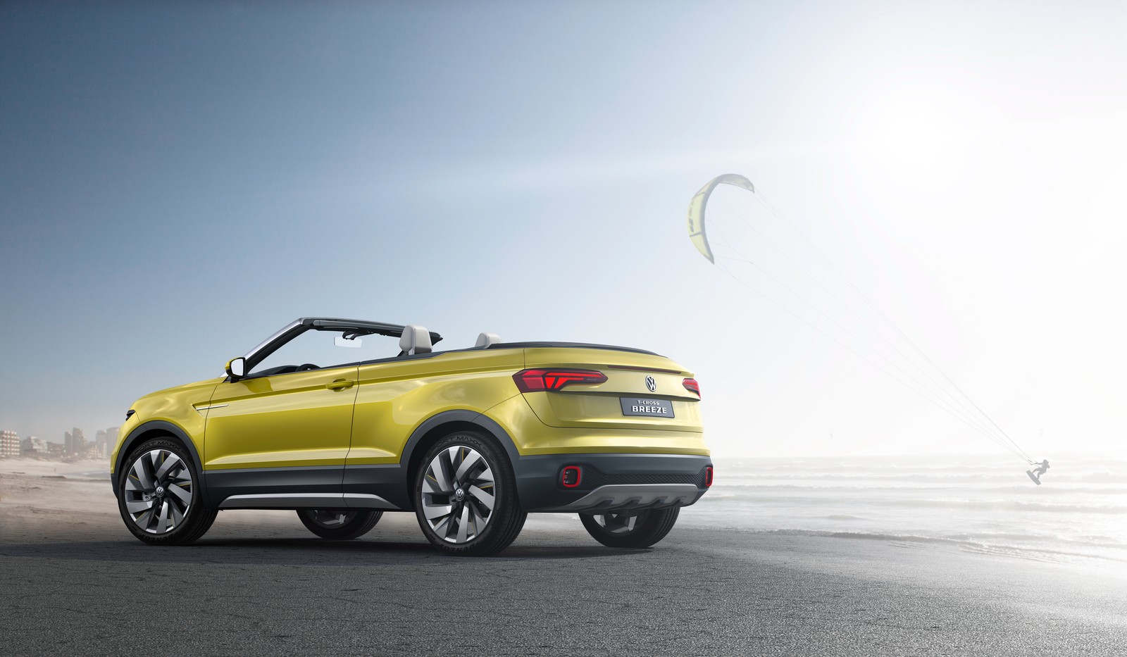 A yellow volkswagen suv parked on the beach with a kite in the sky (car, volkswagen, yellow, convertible, geneva motor show)