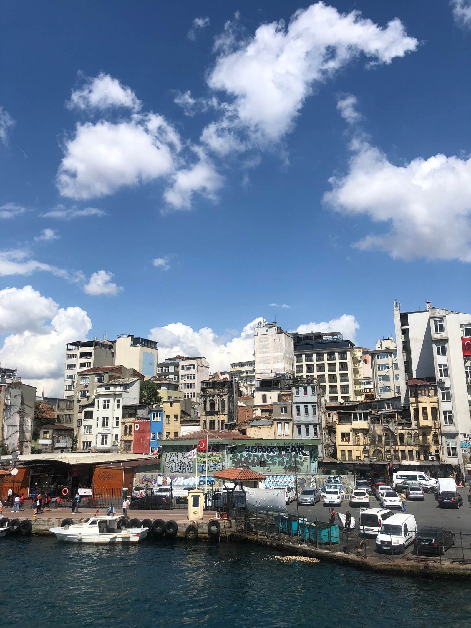 There is a large body of water with a lot of buildings in the background (cloud, waterway, water, watercraft, neighbourhood)