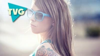 Fille cool avec des lunettes de soleil, des cheveux longs et des tatouages