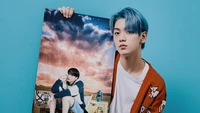 Soobin from Tomorrow X Together showcasing a poster during a vibrant photoshoot, embodying a dreamy aesthetic.