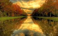 Autumn Reflection: A Serene Waterway Framed by Vibrant Trees and a Colorful Sky