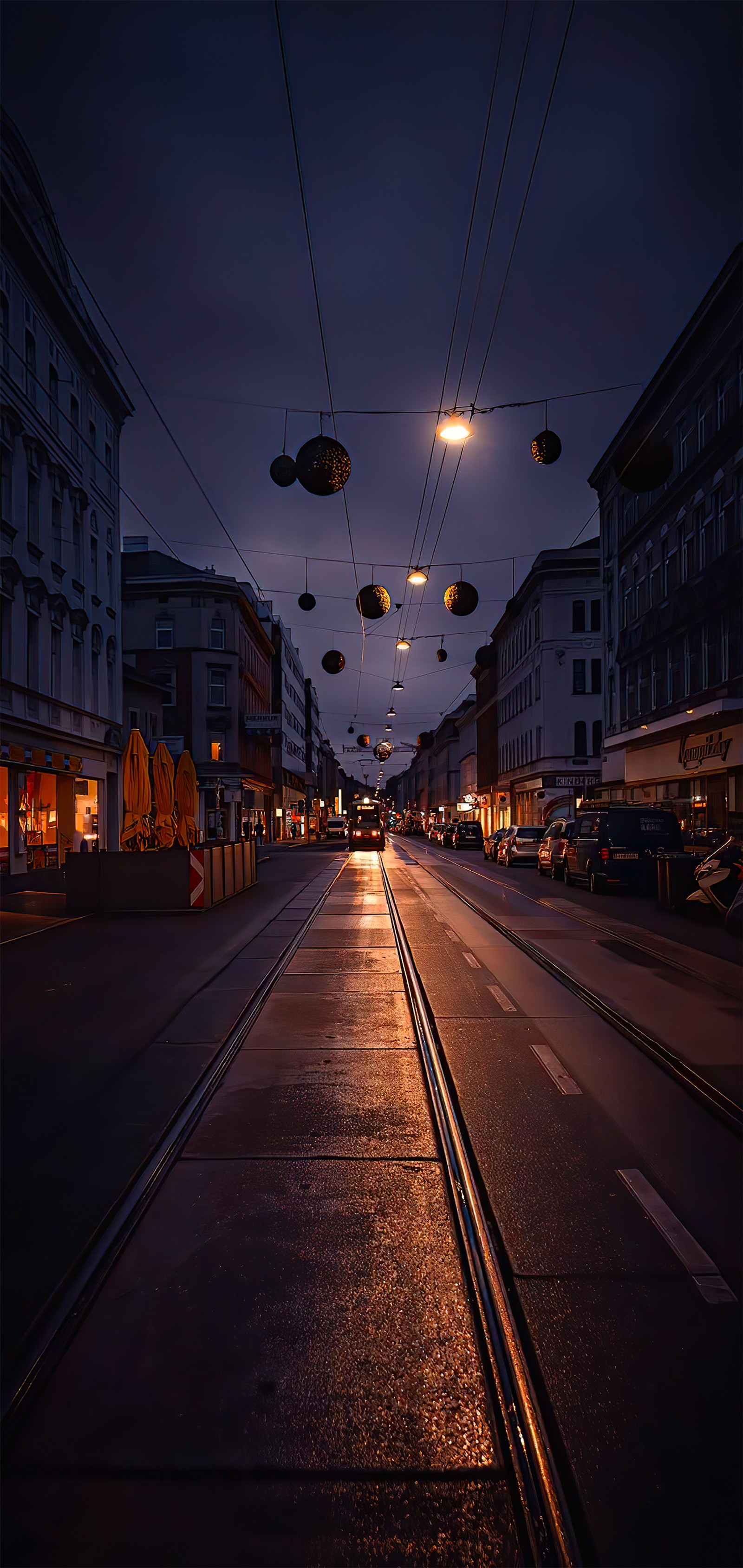 There are many lights hanging over a city street at night (building, atmosphere, window, road surface, infrastructure)