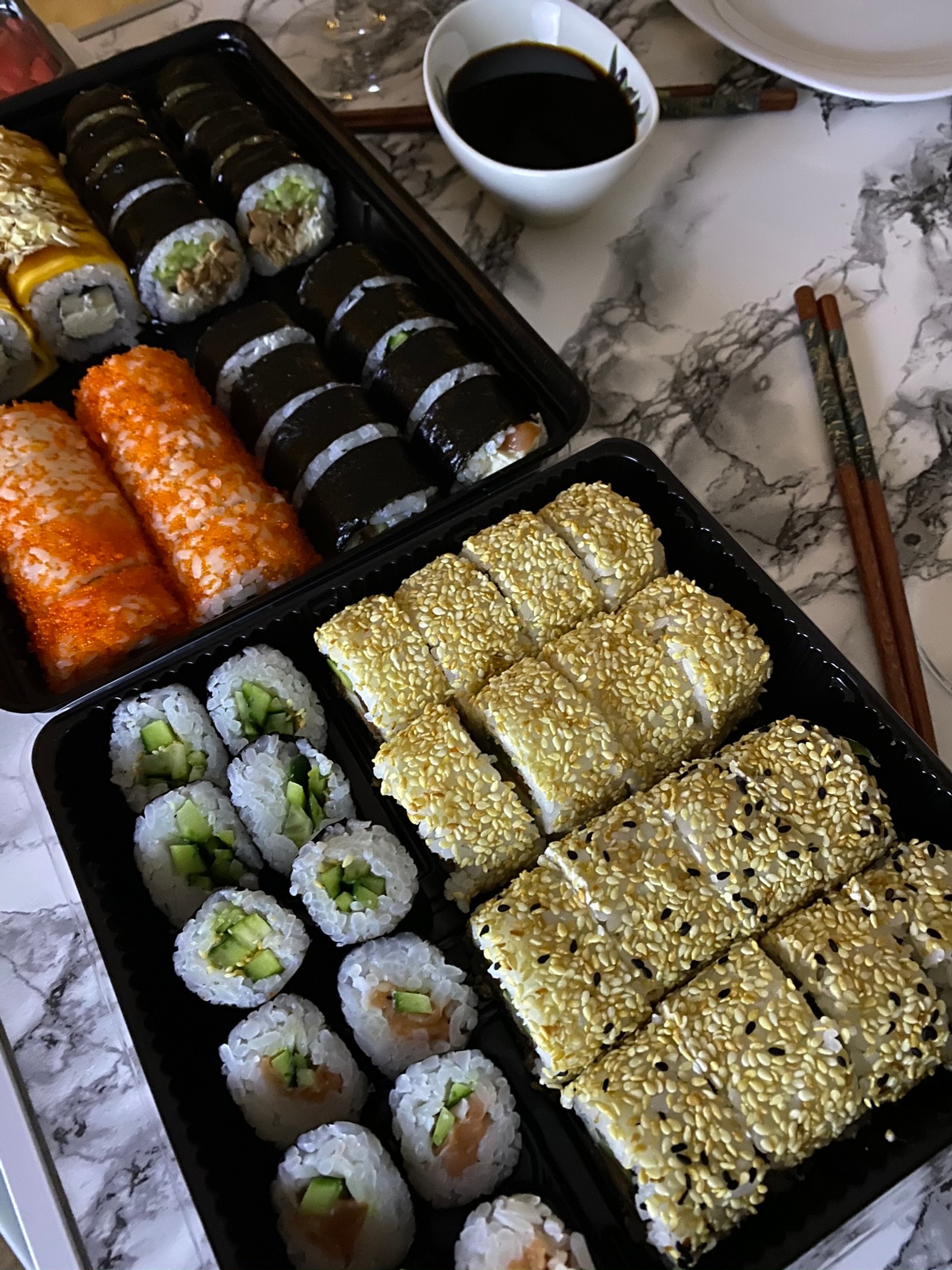 Há duas bandejas de sushi e rolos na mesa (comida reconfortante, comida de dedo, refeição, acompanhamento, comida)