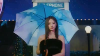 Tzuyu de TWICE sous un parapluie fantaisiste, illuminée par un fond de lumière lunaire rêveuse.