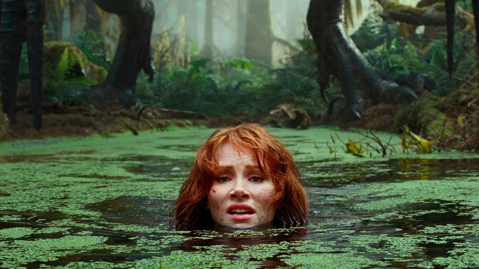 Una mujer árabe en un pantano con un dinosaurio gigante de fondo (jurassic world dominion, película, 2022, bryce dallas howard, claire dearing)