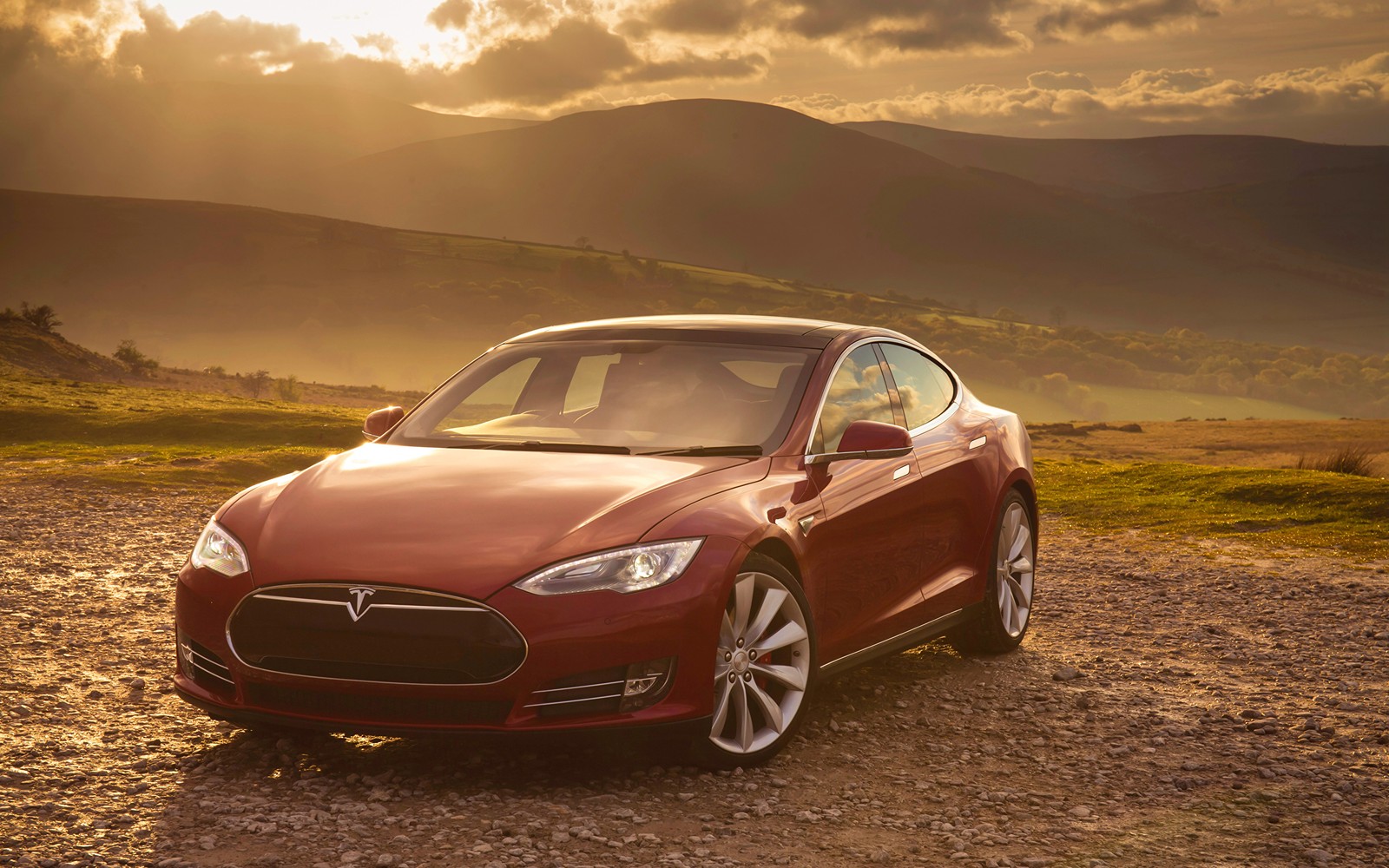 Un tesla model s rojo estacionado en un camino de tierra frente a montañas (tesla model s, tesla model 3, tesla model x, coche, coche mediano)