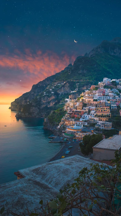 Dreamy Coastal Landscape at Sunset with Moonlit Mountains and Vibrant Village