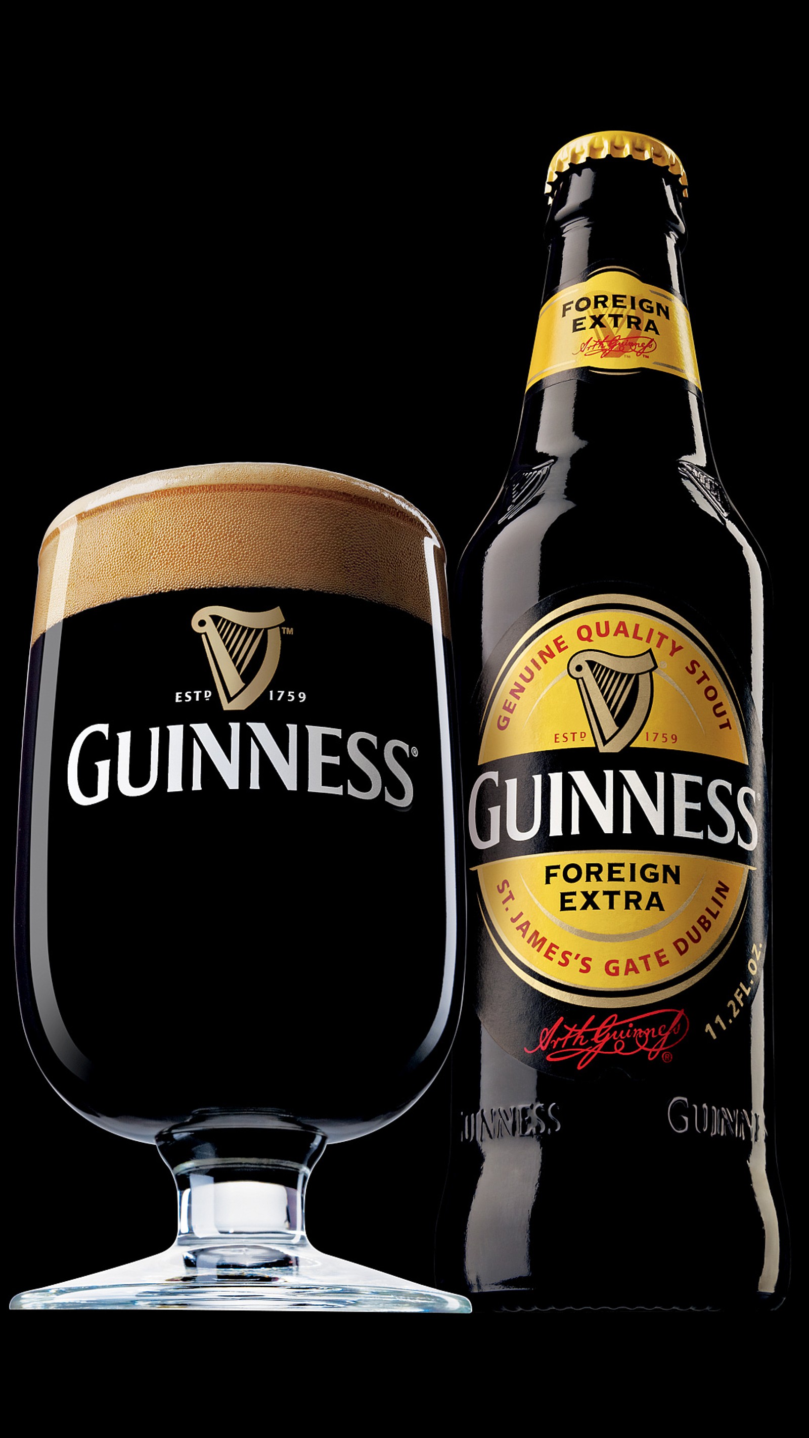 Um copo de cerveja guinness ao lado de uma garrafa de cerveja (guinness, stout)