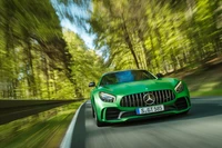 Dynamischer grüner Mercedes-Benz AMG GT rast durch einen üppigen Wald