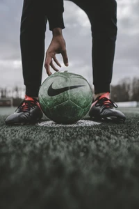 A football player prepares to dribble a vibrant green Nike soccer ball on a turf pitch.