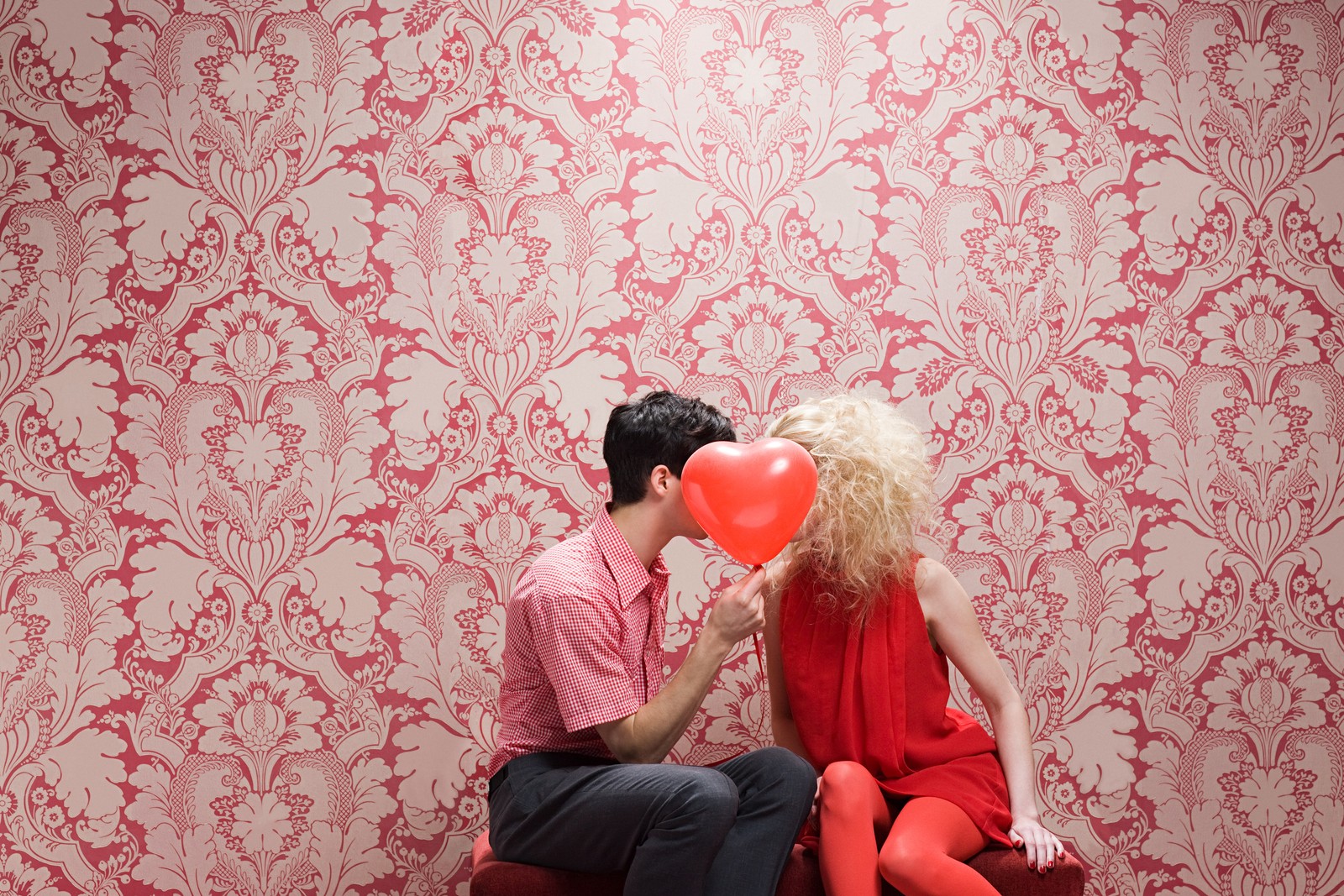 Están sentados en un banco con un globo rojo en la boca (rojo, rosa, amor, romance, interacción)