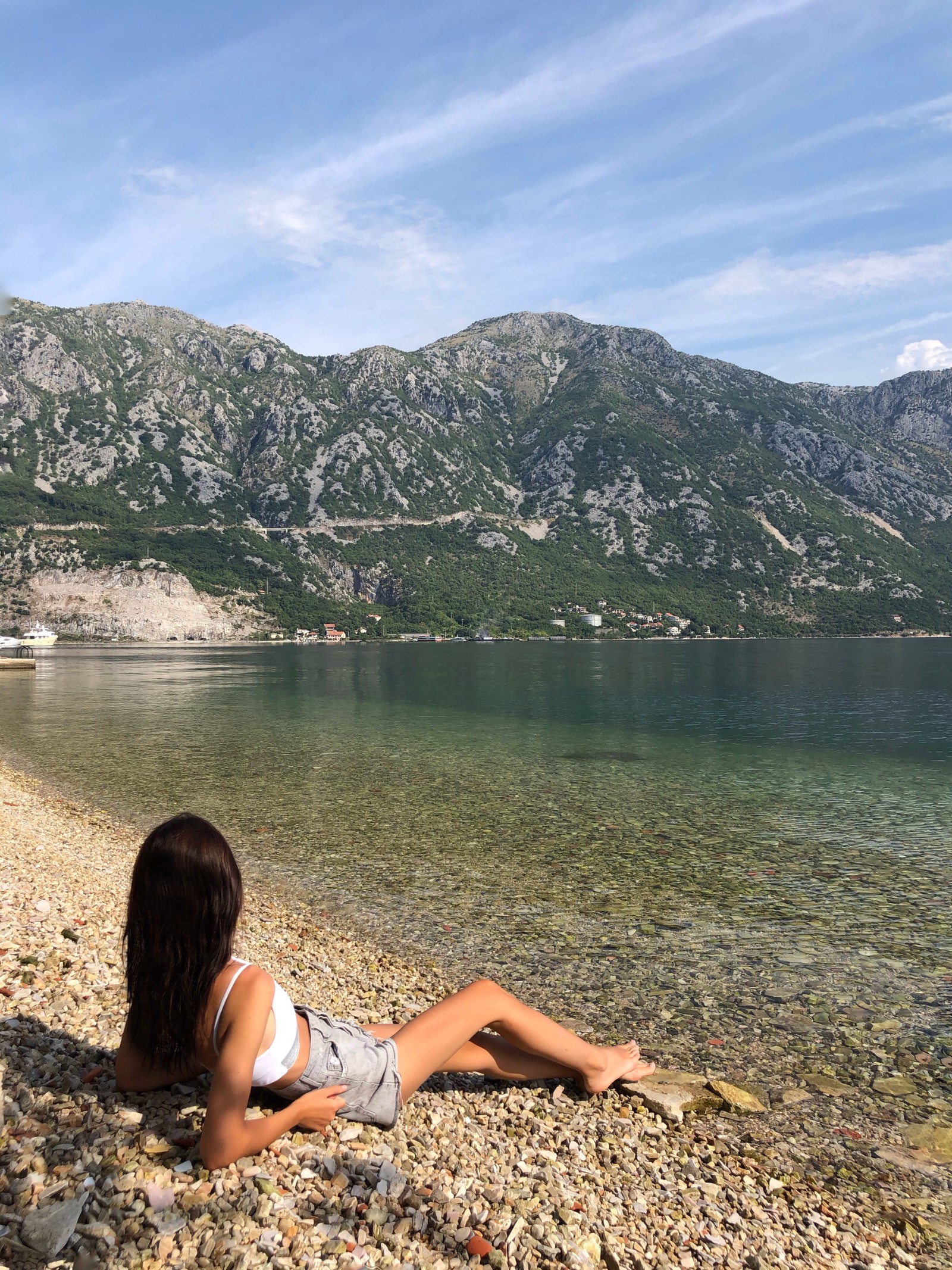 Une femme est assise sur la plage en regardant l'eau (fjord, eau, montagne, tourisme, plan deau)