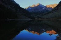 Majestic mountains reflected in a serene glacial lake at dusk.