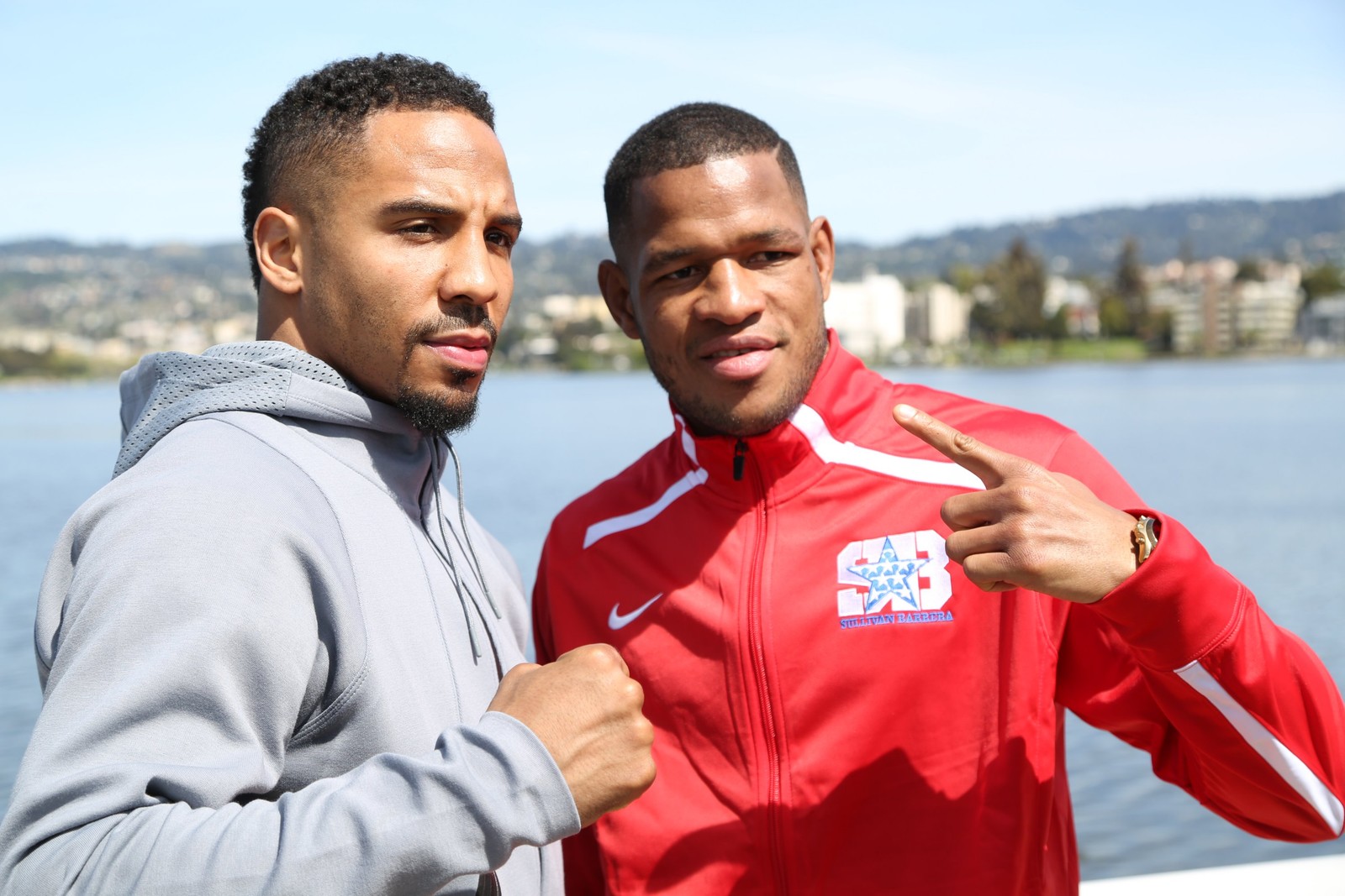 Dois homens em pé um ao lado do outro perto de um corpo d'água (boxe, diversão, recreação, equipe, gesto)