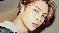 Johnny de NCT 127 con una mirada impactante y un cabello elegante, mostrando una mezcla de carisma y moda contemporánea.