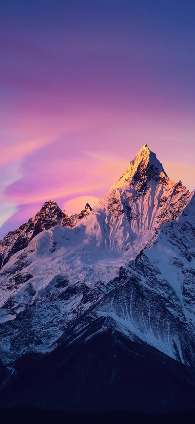 Cima de montaña nevada al atardecer con cielos vibrantes