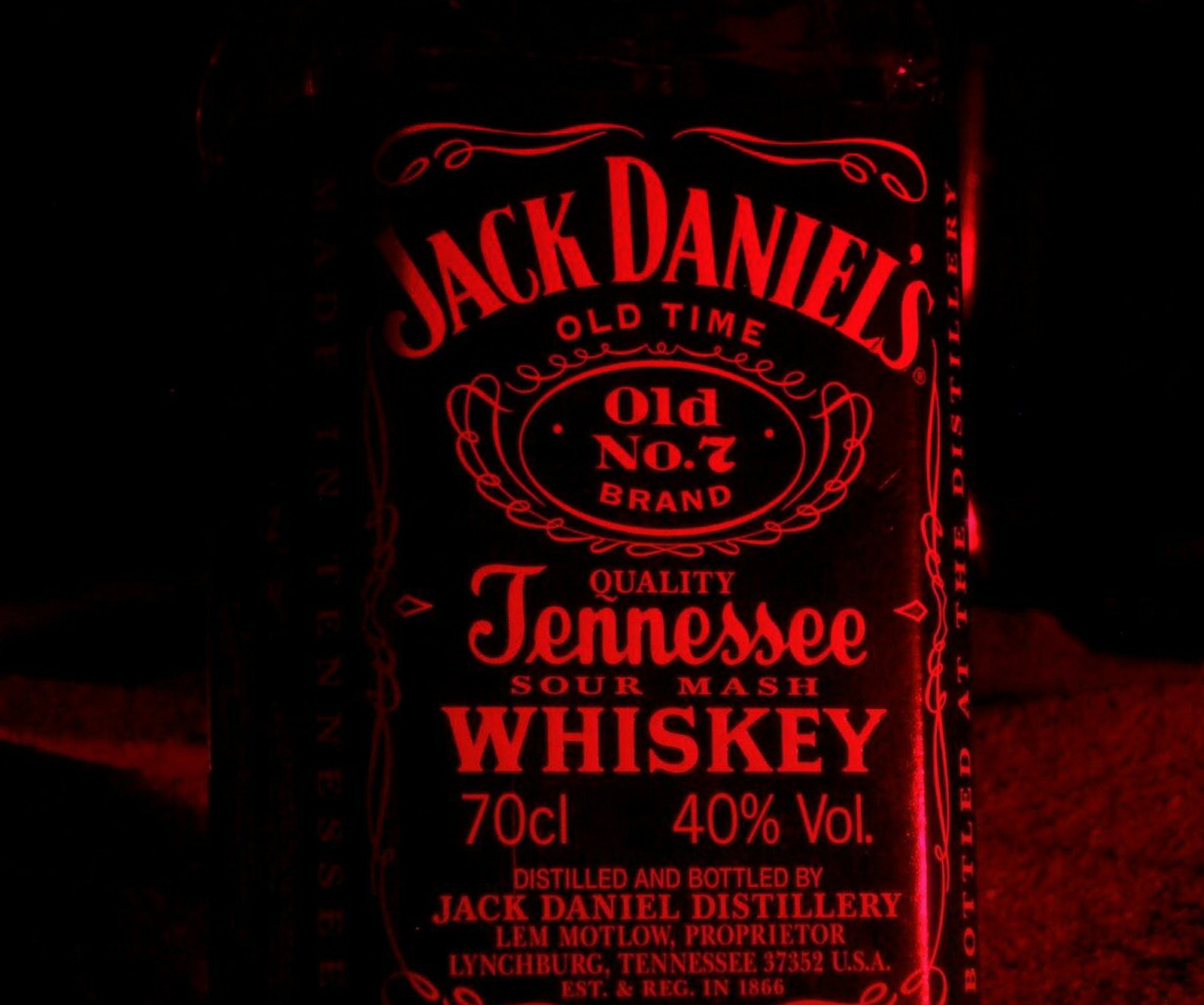 Eine nahaufnahme einer jack daniels whiskey-flasche, die nachts beleuchtet ist (flasche, daniels, jack)