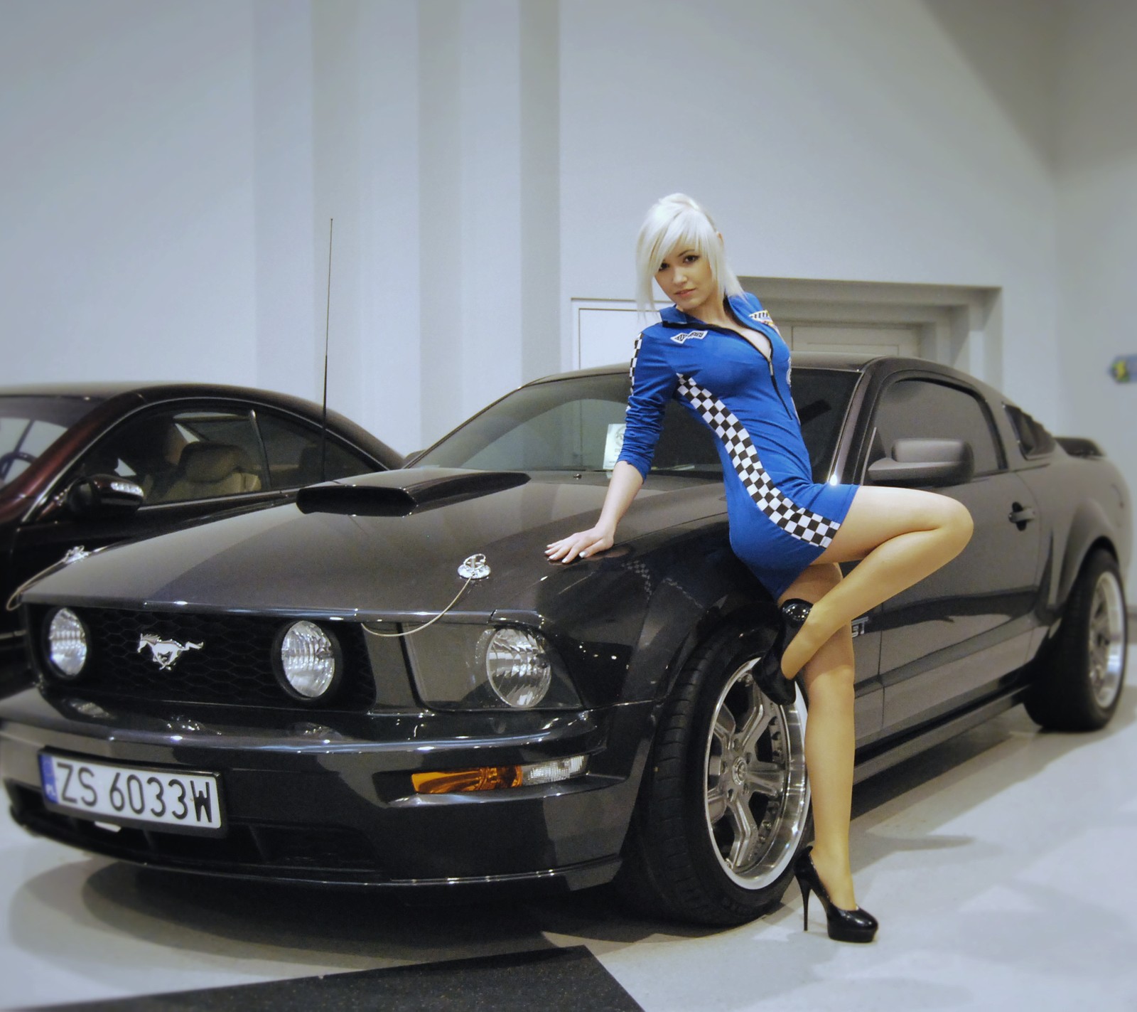 Femme arafa en robe bleue s'appuyant sur une mustang noire (voiture, voitures, bon, modèle, moteurs)