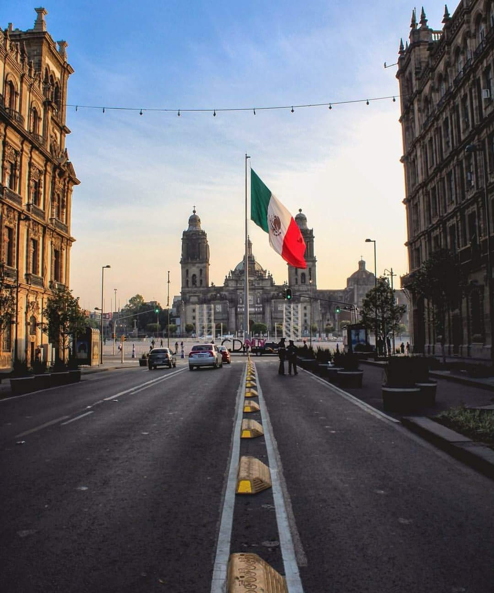 Una vista de una calle de la ciudad con una bandera ondeando en el aire (ciudad, bandera, paisaje, amor, méxico)