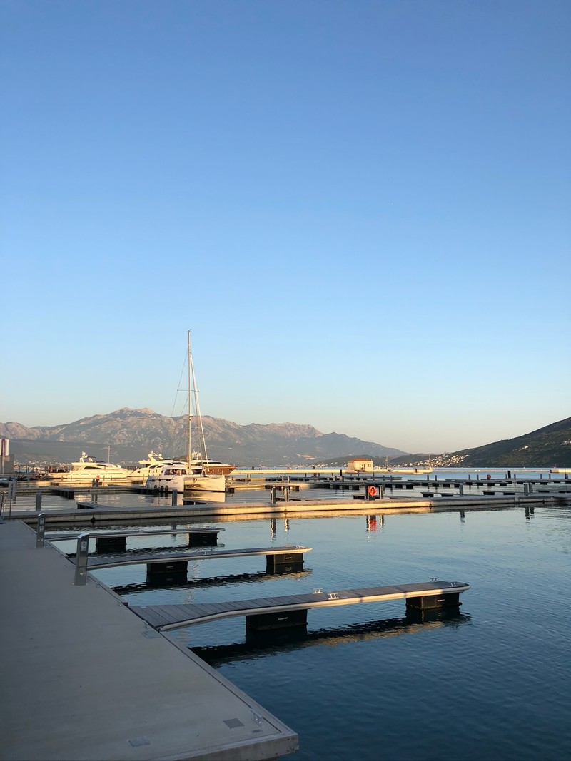 Лодка пришвартована к причалу с горой на заднем плане (паром, ferry, вода, горный хребет, холм)