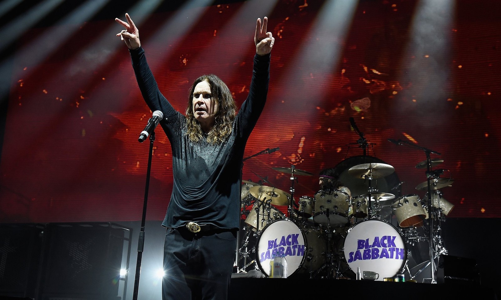 Hombre artístico con los brazos levantados en el escenario (ozzy osbourne, the end tour, black sabbath, desempeño, artista musical)