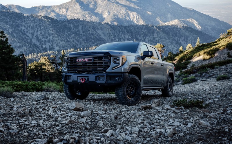 Серый грузовик, припаркованный на каменистой дороге перед горами (gmc sierra, 2023, 5k, машины, обои 4k)