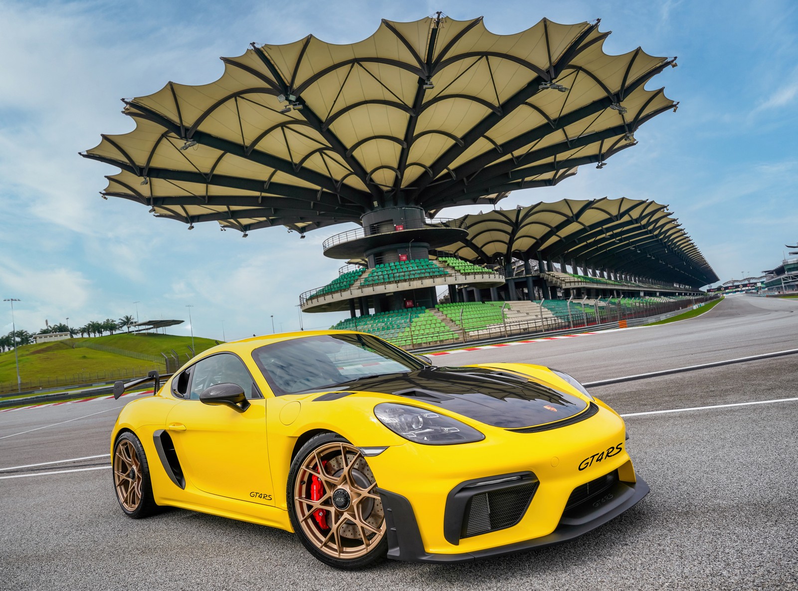 A yellow porsche gts sits on the track in front of a large umbrella (porsche 718 cayman gt4 rs, sports cars, yellow cars, yellow porsche, 5k)