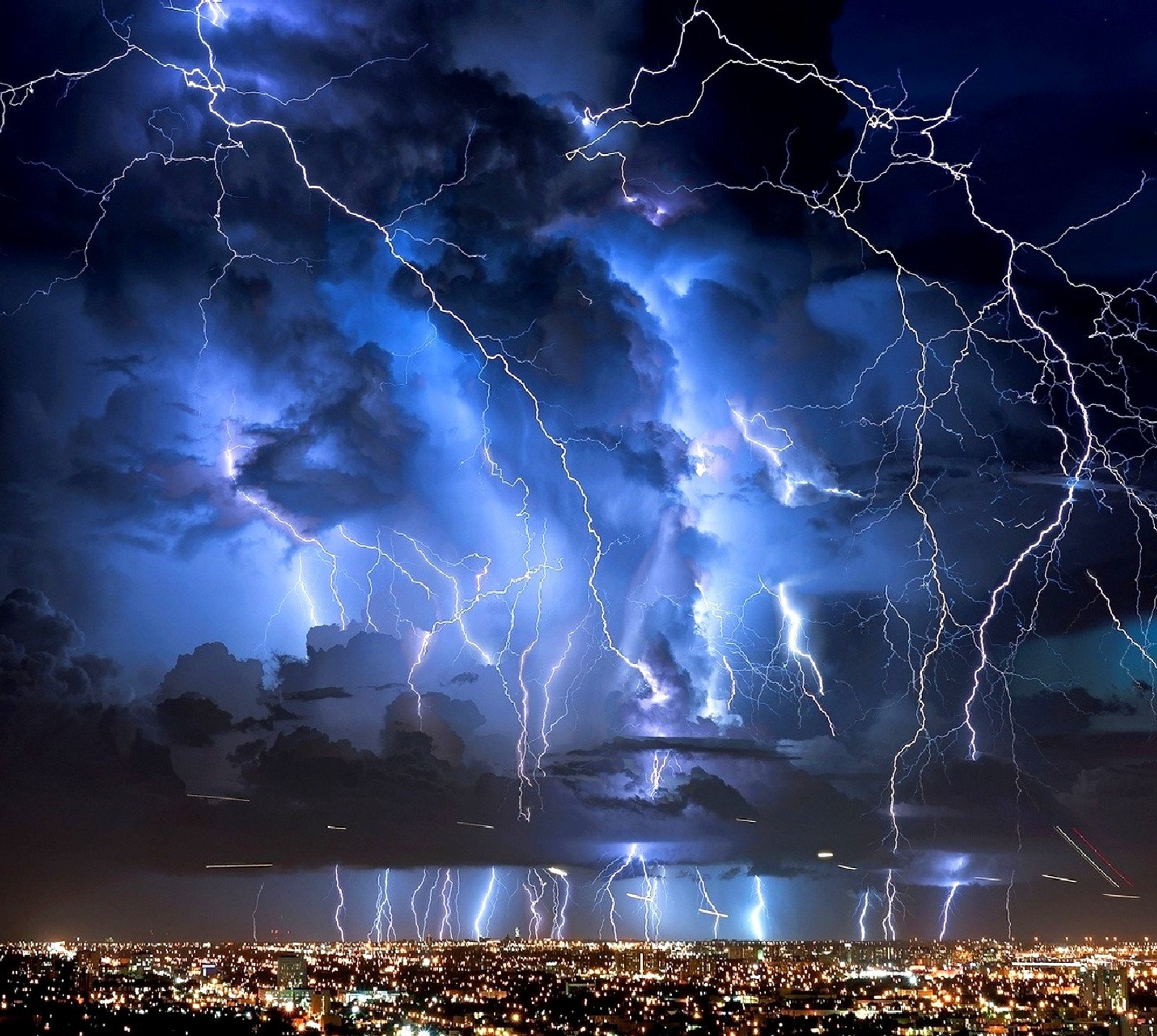 Lightning strikes over a city at night with a dark sky (storm)