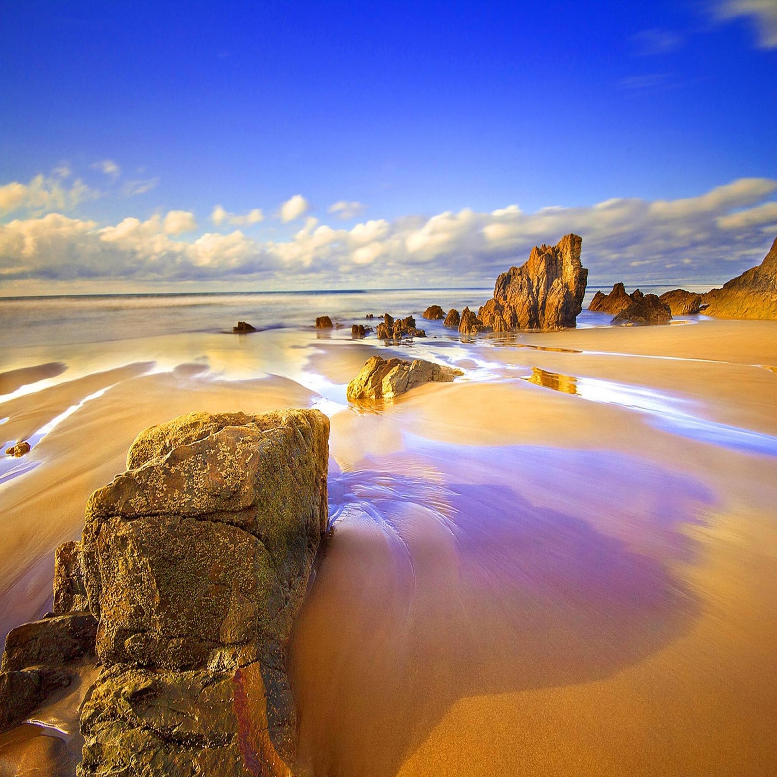 Arafed rocks on a sandy beach with a blue sky (beautiful, cute, look, nice)