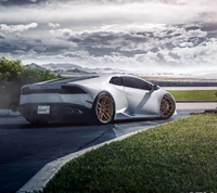 Lamborghini Huracán élégant avec des roues personnalisées garé contre un paysage dramatique.