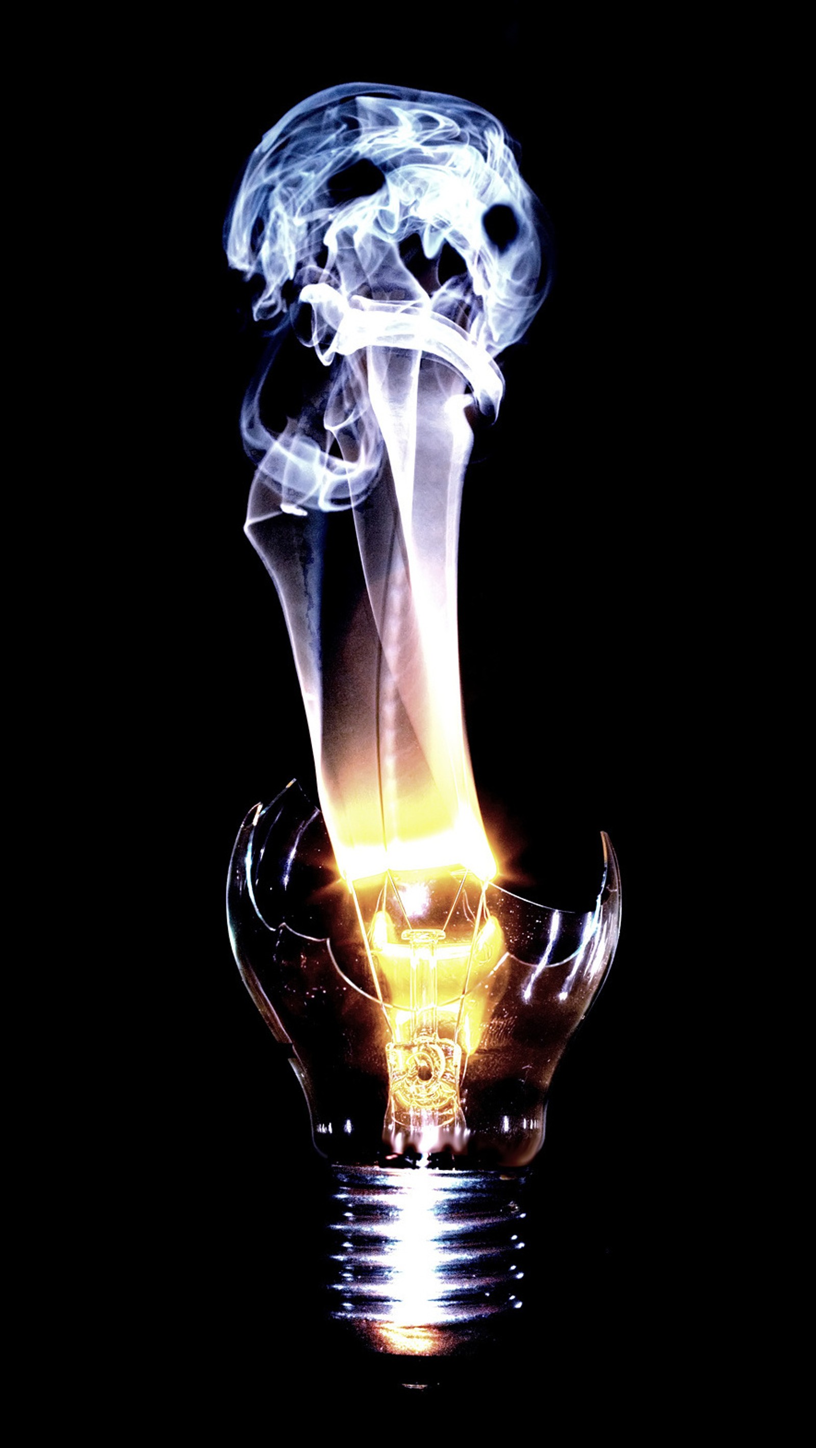 Smoke billowing out of a light bulb with a black background (broken, bulb)