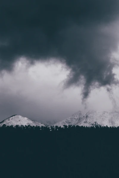 Schneebedeckte Berge unter dramatischem bewölkten Himmel