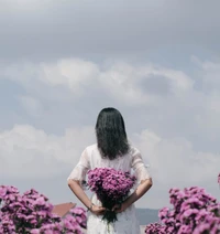 Accueillir le printemps : une femme avec un bouquet de fleurs de lavande contre un ciel nuageux