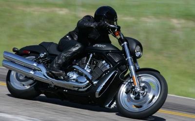 Cavalier en cuir sur une Harley Davidson V-Rod personnalisée à grande vitesse sur une route ouverte