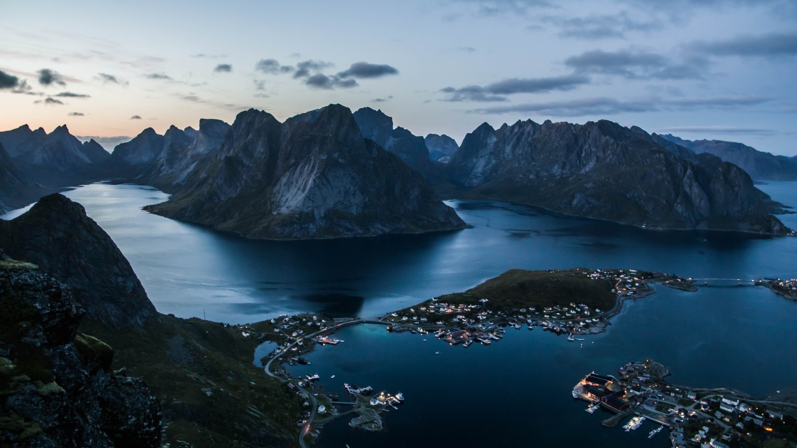 Uma vista de uma cadeia montanhosa com um corpo d'água e uma cidade (lofoten, vila de pescadores, nuvem, água, montanha)