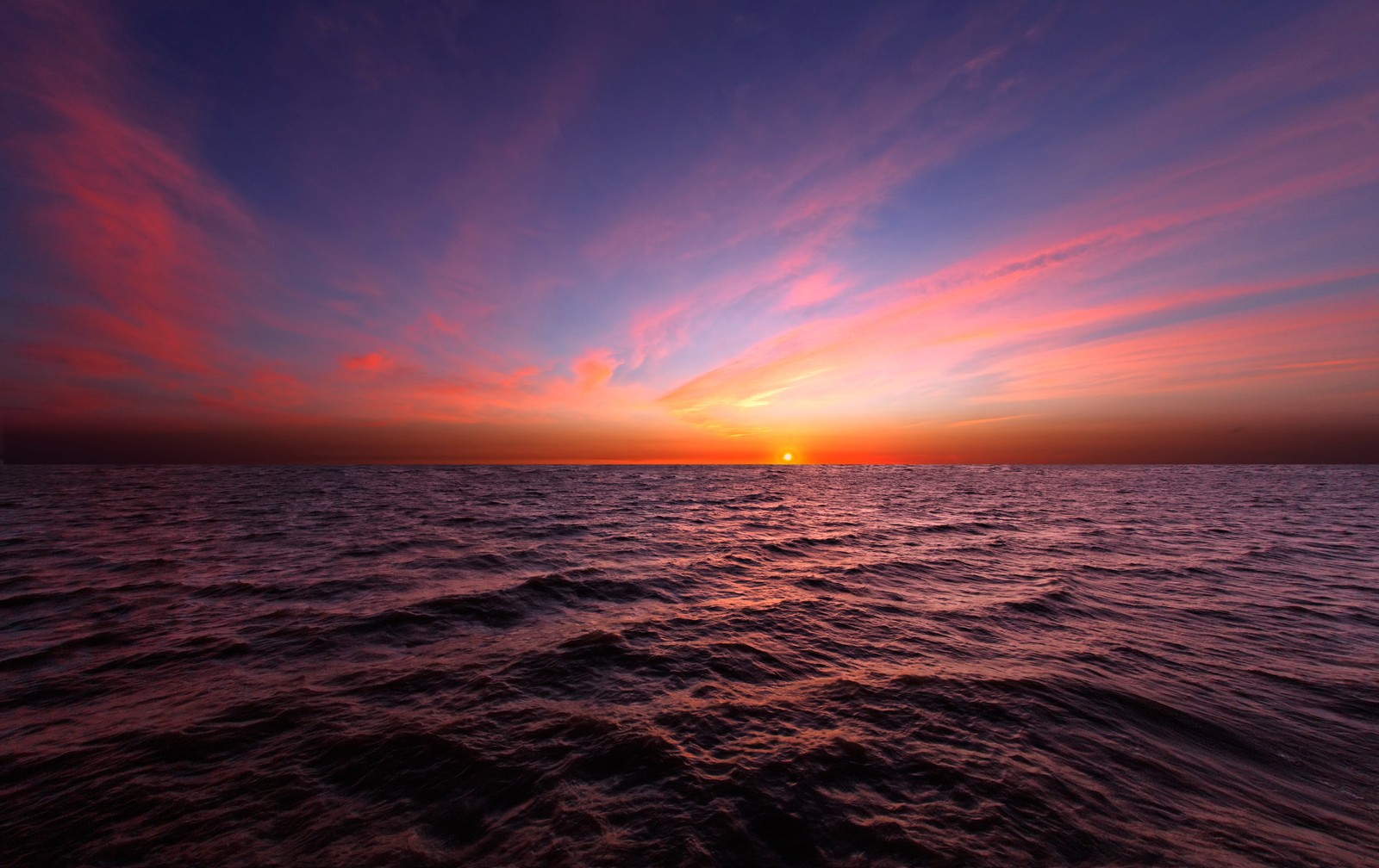 Un atardecer sobre el océano con un cielo naranja brillante (atardecer, horizonte, mar, océano, amanecer)